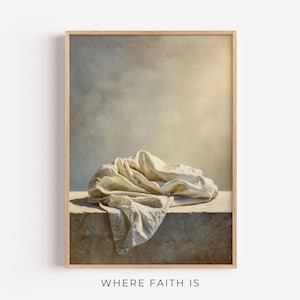 May include: A framed art print featuring a draped, off-white cloth resting on a stone surface. The background has a soft, neutral color palette with a warm, golden light. The text "WHERE FAITH IS" is printed at the bottom.
