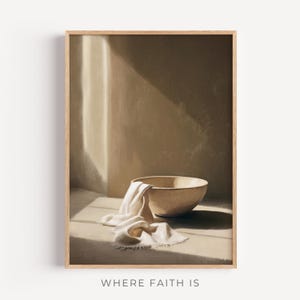 May include: A framed print depicting a still life scene. A beige ceramic bowl with a white cloth is on a light surface. The background is a neutral beige with a beam of light. The text "WHERE FAITH IS" is at the bottom of the image.