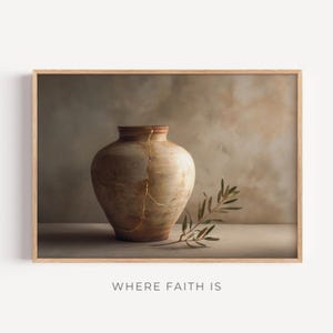 Op de afbeelding: Een ingelijste print met een beige, gebarsten vaas met gouden accenten en een takje groene bladeren. De tekst "WHERE FAITH IS" staat onderaan de afbeelding. Het kunstwerk heeft een neutraal kleurenpalet.