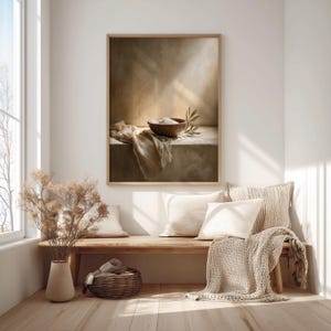 May include: A framed art print depicts a still life with a wooden bowl filled with white substance, a draped cloth, and an olive branch. The artwork is in a warm, neutral color palette, with soft lighting and a rustic aesthetic.