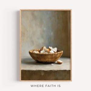 Puede incluir: Impresión enmarcada que presenta una naturaleza muerta de pan en una cesta de mimbre. El pan es marrón claro y blanco, con algunas piezas esparcidas. El texto "WHERE FAITH IS" está en la parte inferior.
