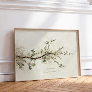 Può includere: Una stampa artistica da parete rettangolare incorniciata raffigurante un ramo d'albero orizzontale con foglie verdi su uno sfondo color crema tenue. Il testo I AM THE VINE You Are The Branches è stampato in un carattere scuro sotto l'illustrazione.