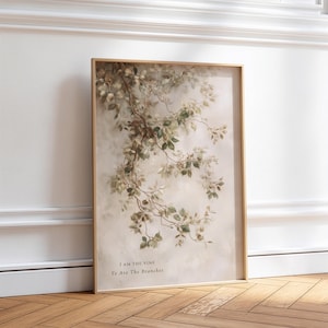 Könnte beinhalten: Ein rechteckiger Wandkunstdruck in einem dünnen goldenen Rahmen mit einer botanischen Illustration von herabhängenden grünen Weinreben auf weichem cremefarbenem Hintergrund. Der Text "I AM THE VINE" und "Ye Are The Branches" ist in kleinen dunklen Buchstaben gedruckt.