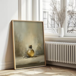 May include: A framed art print featuring a still life of a glass bottle with a cork stopper, filled with a golden liquid. The painting includes a sprig of leaves and berries, set against a muted, neutral background. The frame is gold.