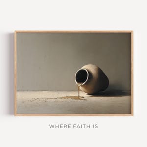 Puede incluir: Impresión enmarcada de una jarra de barro beige volcada, con líquido derramándose sobre una superficie clara. El fondo es gris neutro. El texto "WHERE FAITH IS" está impreso en la parte inferior.
