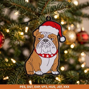May include: A brown and white bulldog ornament wearing a red Santa hat and a red collar with white stars. The ornament features a black embroidered border and a gold hanging string. Text at the bottom reads: PES, DST, EXP, VP3, HUS, JEF, XXX.