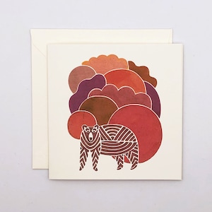 May include: A brown bear with a striped pattern stands in front of a background of overlapping circles in shades of red, orange, and purple.