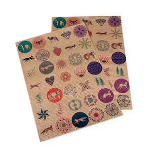 Könnte beinhalten: Zwei Bögen dekorativer Aufkleber mit einem Hintergrund aus Kraftpapier. Die Aufkleber zeigen verschiedene Designs, darunter Füchse, geometrische Formen und florale Muster in Rot-, Grün-, Blau- und Brauntönen. Die Aufkleber sind in Kreisen und anderen Formen angeordnet.