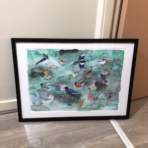 May include: A framed watercolour painting of a variety of birds on a green background. The birds are depicted in various poses, some flying, some perched, and some in mid-flight. The painting is framed in a black frame.