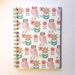 May include: A white spiral bound notebook with a pink and orange owl and flower pattern.