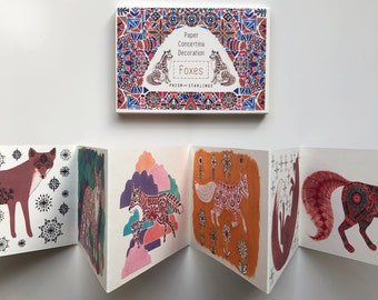 Puede incluir: Una decoración de papel concertina con un patrón geométrico colorido y el texto "Paper Concertina Decoration Foxes Prism & Starlings". La decoración presenta una serie de ilustraciones de zorros con intrincados patrones.