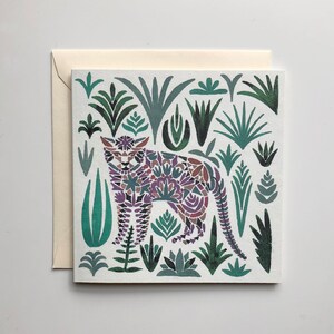 Puede incluir: Una tarjeta blanca con una ilustración colorida de un leopardo estilizado rodeado de follaje verde. El leopardo está hecho de una variedad de formas geométricas moradas, rosas y azules.