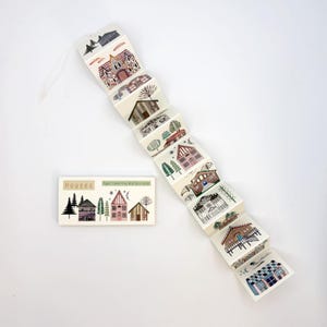 May include: A decorative paper accordion featuring illustrations of various houses, with a matching rectangular card that reads "Houses" and "Paper Concerning Wall Decoration". The houses are depicted in a variety of styles and colors.