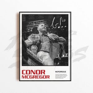 May include: Black and white framed poster featuring Conor McGregor, holding championship belts. The poster includes the name "CONOR MCGREGOR" in red text, with the word "NOTORIOUS" and a brief description below. A signature is visible at the top.