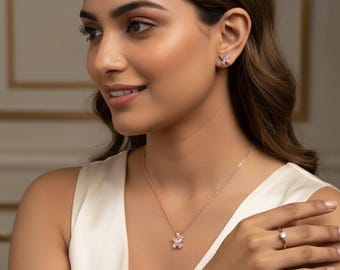 May include: A rose gold jewelry set featuring a floral design. The set includes a necklace, earrings, ring, and bracelet, all adorned with clear gemstones. The woman is wearing a white top.