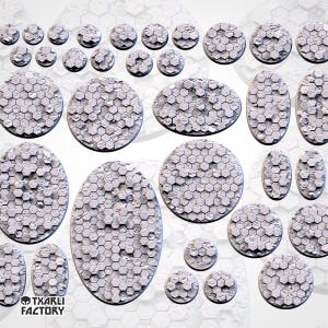 Pode incluir: Uma coleção de bases cinzentas texturizadas com padrão hexagonal, de vários tamanhos, para figuras em miniatura. As bases têm formas redondas, ovais e irregulares, adequadas para jogos de mesa. A imagem mostra uma variedade de tamanhos e formas.