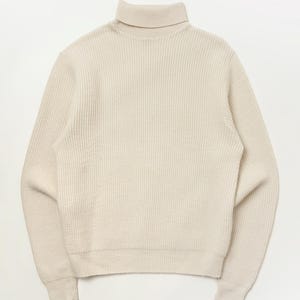 May include: A white ceramic mug with a black handle and the text "But First, Coffee" in a black, bold font. The mug is on a white surface. The mug is likely used for hot beverages.