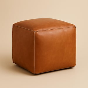 May include: A square, brown leather ottoman. The cube-shaped furniture piece has a smooth, seamless design with rounded edges. The leather has a warm, natural tone, and the ottoman is set against a neutral background.