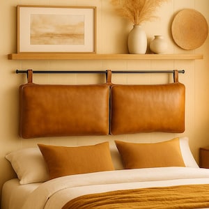 May include: A bedroom scene featuring a bed with a brown leather headboard and matching pillows. The headboard is suspended from a black metal bar. The bed is made with white sheets and a mustard-colored throw blanket. A wooden shelf above the bed holds decorative items.