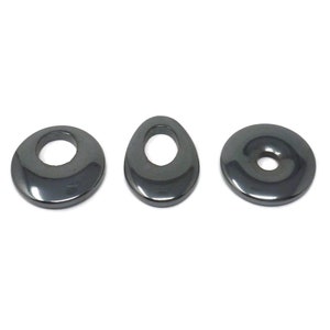 May include: Three black hematite gemstone beads with a hole in the center. The beads are in the shape of a circle, an oval, and a flat disc.