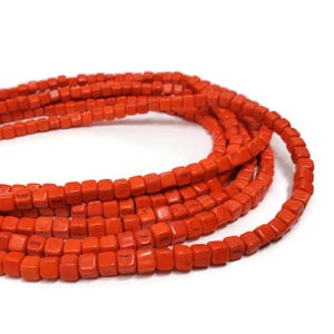 May include: A strand of orange square beads. The beads are made of natural stone and have a slightly rough texture.