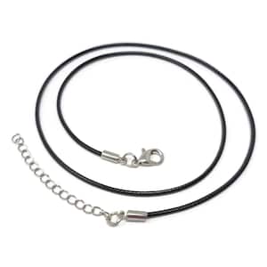 May include: A black necklace cord with a silver-colored clasp and extender chain. The cord is round and appears to be made of a smooth, flexible material. The clasp and extender chain are made of metal.