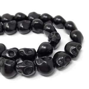 May include: A strand of black skull beads. The beads are made of polished black stone and have a detailed skull design.