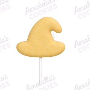 May include: A light tan, witch hat-shaped cookie on a thin white stick. The cookie has a smooth, uniform surface texture and a curved, pointed top section with a wide brim base, presented against a white background with repeating Aerabella Cookies text.