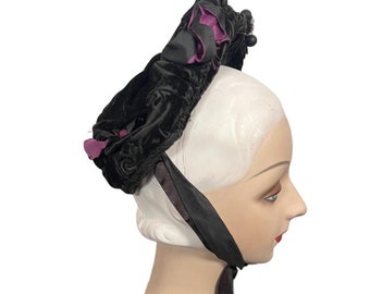 May include: A black velvet hat with a purple satin bow and a long black satin ribbon.