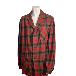 May include: A red, black, and olive green plaid jacket with a notched collar, two front pockets, and three buttons. The jacket is displayed on a white mannequin.