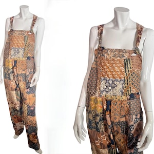 Op de afbeelding: Een patchwork jumpsuit in bruin-, beige- en marineblauwtinten. De jumpsuit heeft een vierkante halslijn, brede bandjes en een relaxte pasvorm. De stof lijkt een mix van patronen te zijn.