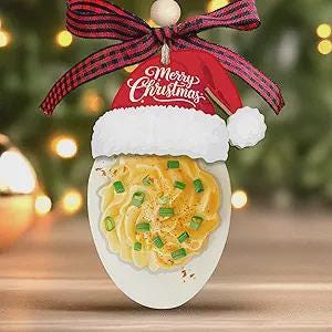 May include: A unique Christmas ornament shaped like an egg, featuring a Santa hat and a decorative food design. The ornament has a red and white Santa hat with the words "Merry Christmas" and a plaid ribbon. The egg design has a yellow food design with green sprinkles.