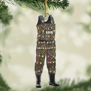 May include: A Christmas ornament shaped like a pair of brown and black fishing waders, decorated with colorful lights. The word "DAVID" is printed on the chest. The waders have black boots and suspenders.