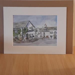 May include: Watercolor painting of a pub, "The Honiton Inn", with a white facade, gray roof, and red door. The artwork is framed in white and set against a brown background.