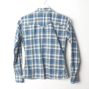 May include: Blue and white plaid long-sleeve shirt hanging on a white hanger. The shirt has a classic button-down design with a pointed collar and buttoned cuffs. The plaid pattern features shades of blue, white, and green.