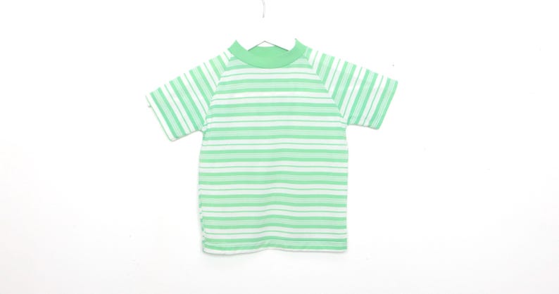 May include: A green and white striped short-sleeved shirt with a mock neck.