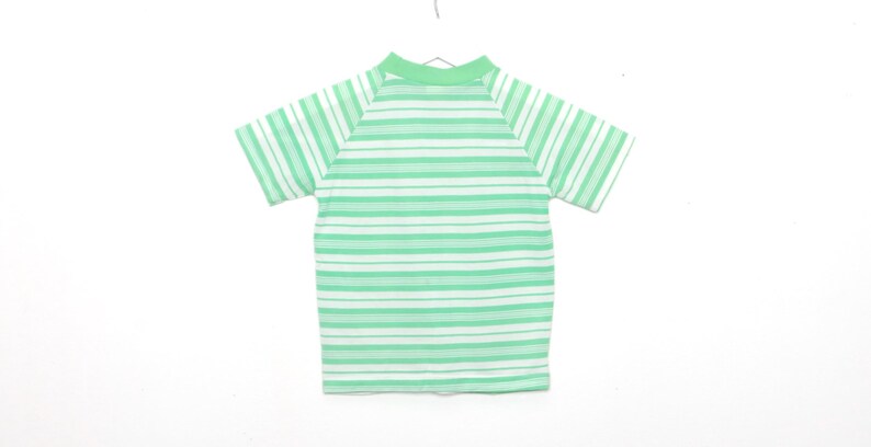 May include: A green and white striped short-sleeved shirt with a mock neck.