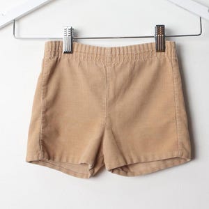 以下が含まれることがあります： 薄い茶色のコーデュロイのショートパンツ。ショートパンツは幅広のウエストバンドとゆったりとしたフィット感です。