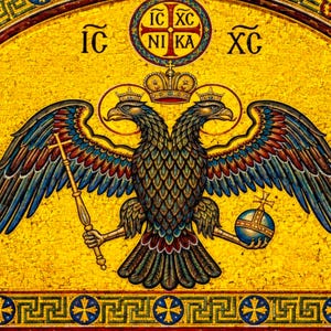 Puede incluir: Mosaico que representa un águila bicéfala coronada, sosteniendo un cetro y un orbe. Las alas del águila son azules, rojas y doradas sobre un fondo dorado. También hay texto griego y una cruz.