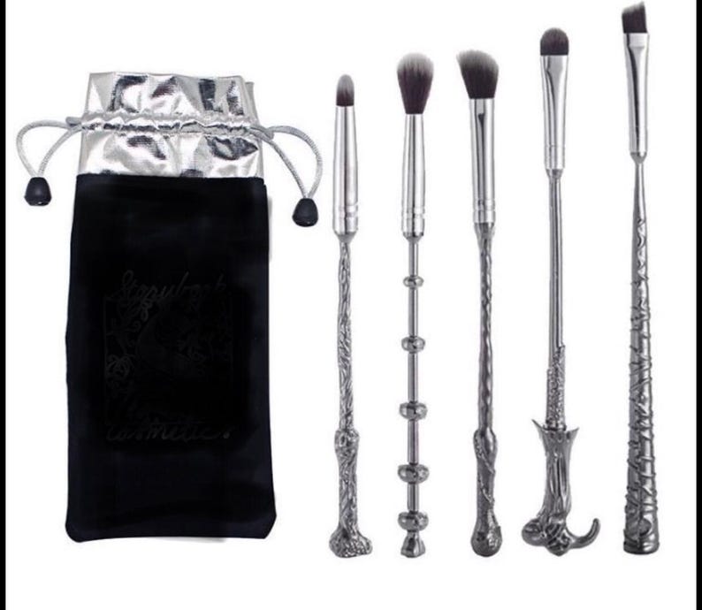 Pu&ograve; includere: Un set di sei pennelli per il trucco con manici argentati ornati e setole nere, insieme a un sacchetto di velluto nero con fodera argentata. Il sacchetto riporta la scritta "Sizzylash cosmetics".