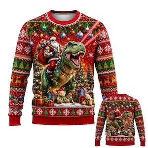Puede incluir: Una sudadera roja de manga larga con cuello redondo que presenta un estampado gráfico de Santa Claus montando un T-Rex verde. El diseño incluye árboles de Navidad, regalos envueltos, ositos de peluche, adornos y copos de nieve.
