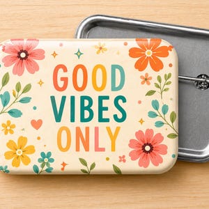 May include: A rectangular button with rounded corners, featuring the phrase "GOOD VIBES ONLY" in colorful letters. The button is decorated with floral and leaf illustrations in shades of pink, orange, yellow, and teal. A silver pin back is attached.