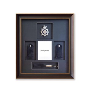 May include: A framed display featuring a police badge, epaulettes, and a whistle. The frame has a dark brown finish with a gold inner border. The display includes a space for a photo with the text "your photo".