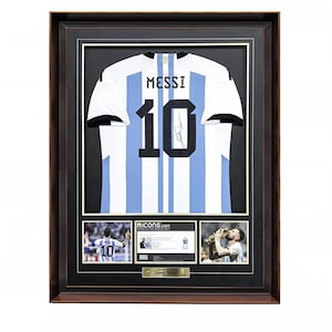 Könnte beinhalten: Ein gerahmtes Display mit einem weiß-hellblau gestreiften Trikot, auf dessen Rückseite der Name MESSI und die Nummer 10 aufgedruckt sind. Unter dem Trikot befinden sich zwei Fotos eines Spielers und ein Echtheitszertifikat in einem dunklen Rahmen.