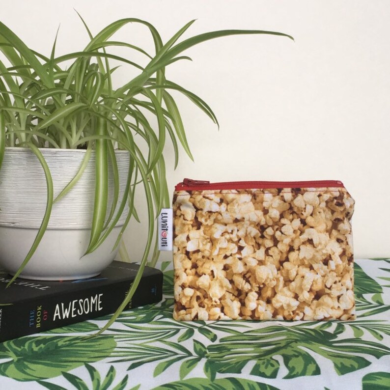 May include: A small zippered pouch with a popcorn print. The pouch is red and white with a zipper pull that says "LumiGuni".