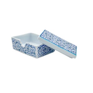 May include: A rectangular white ceramic box with a detached lid, featuring a continuous blue and teal floral vine pattern across the exterior surfaces. The box has a notched front edge, and the interior is plain white with a smooth finish.