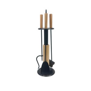 May include: A fireplace tool set featuring a black metal stand with a circular base. The set includes a poker, a shovel, and a brush, each with a light brown wooden handle. The tools are arranged vertically within the stand for storage and access.