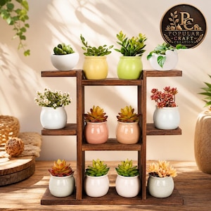 May include: A dark brown wooden tiered plant stand holding eleven small ceramic pots with various succulents and green plants. The pots are in shades of white, yellow, light green, pink, and peach. A circular logo reads Popular Craft Creation.