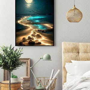 May include: A framed art print depicts a nighttime beach scene with a full moon, sparkling water, and glowing sand. The artwork features a dark blue sky, a bright moon, and a path of illuminated water leading to the horizon. The overall theme is a serene coastal landscape.