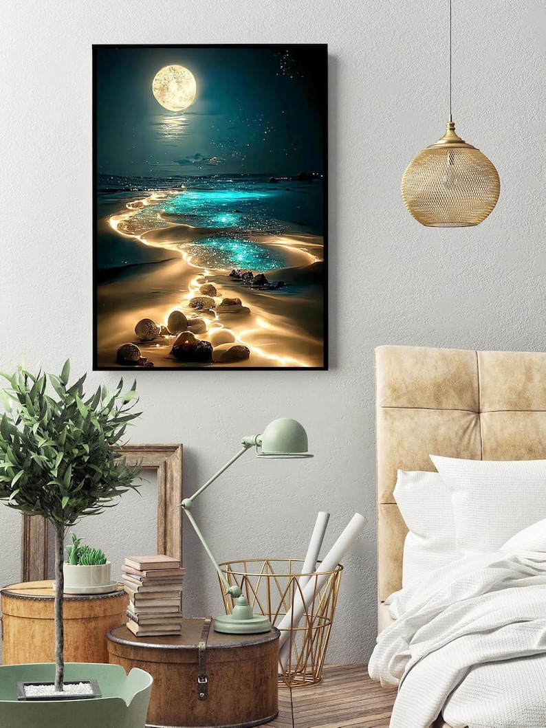 May include: A framed art print depicts a nighttime beach scene with a full moon, sparkling water, and glowing sand. The artwork features a dark blue sky, a bright moon, and a path of illuminated water leading to the horizon. The overall theme is a serene coastal landscape.
